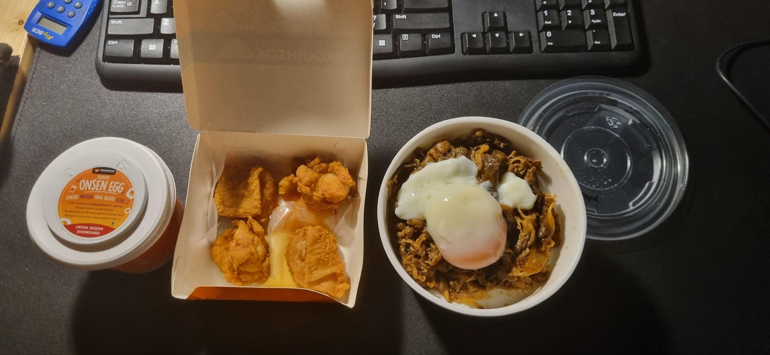 Yoshinoya foods on a computer desk: Onsen Egg, Yakiniku Beef Bowl, Chicken Karaage.